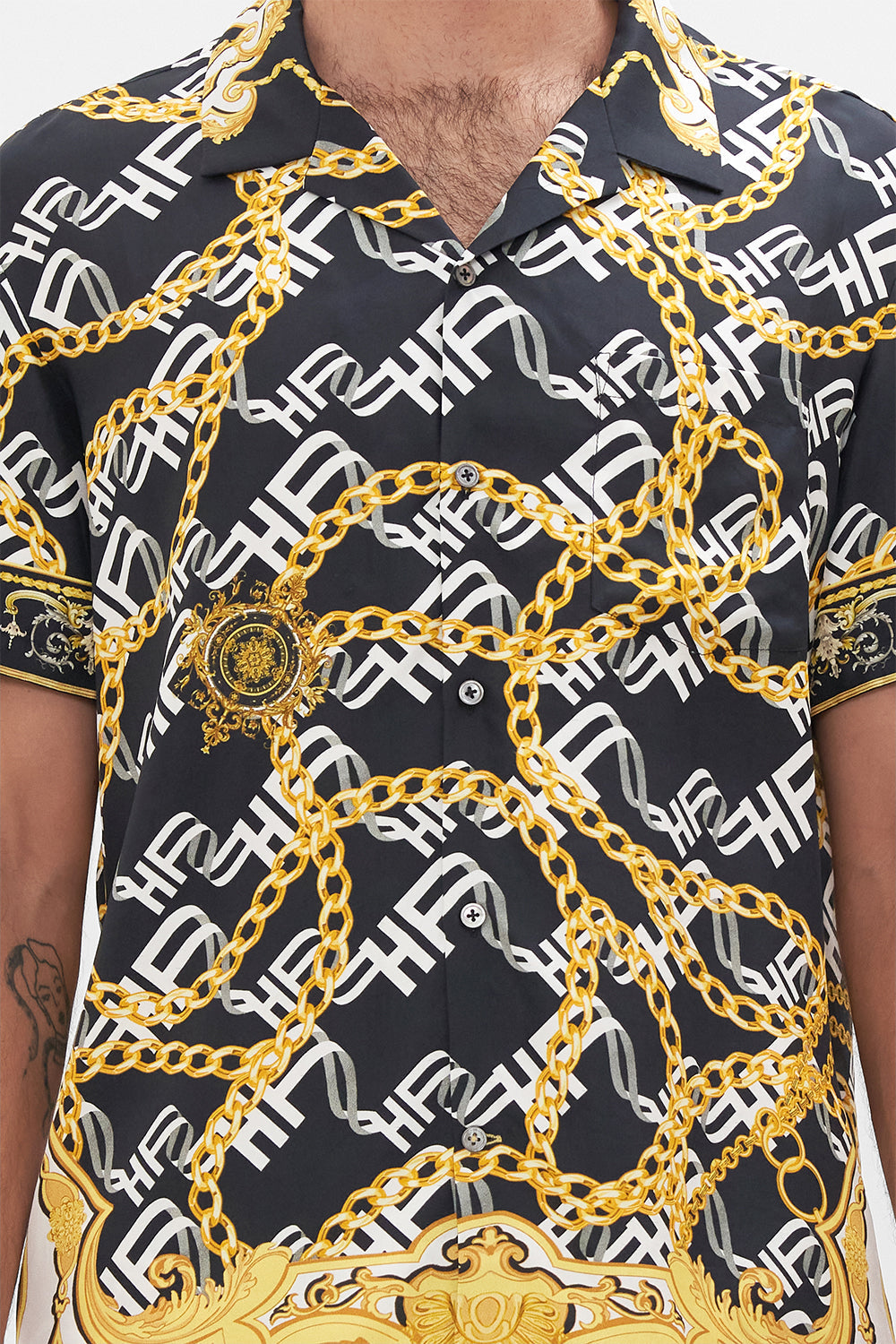 Detail view of model wearing Hotel Franks by CAMILLA mens silk short sleeve camp collared shirt in black and gold Tether Me Not print