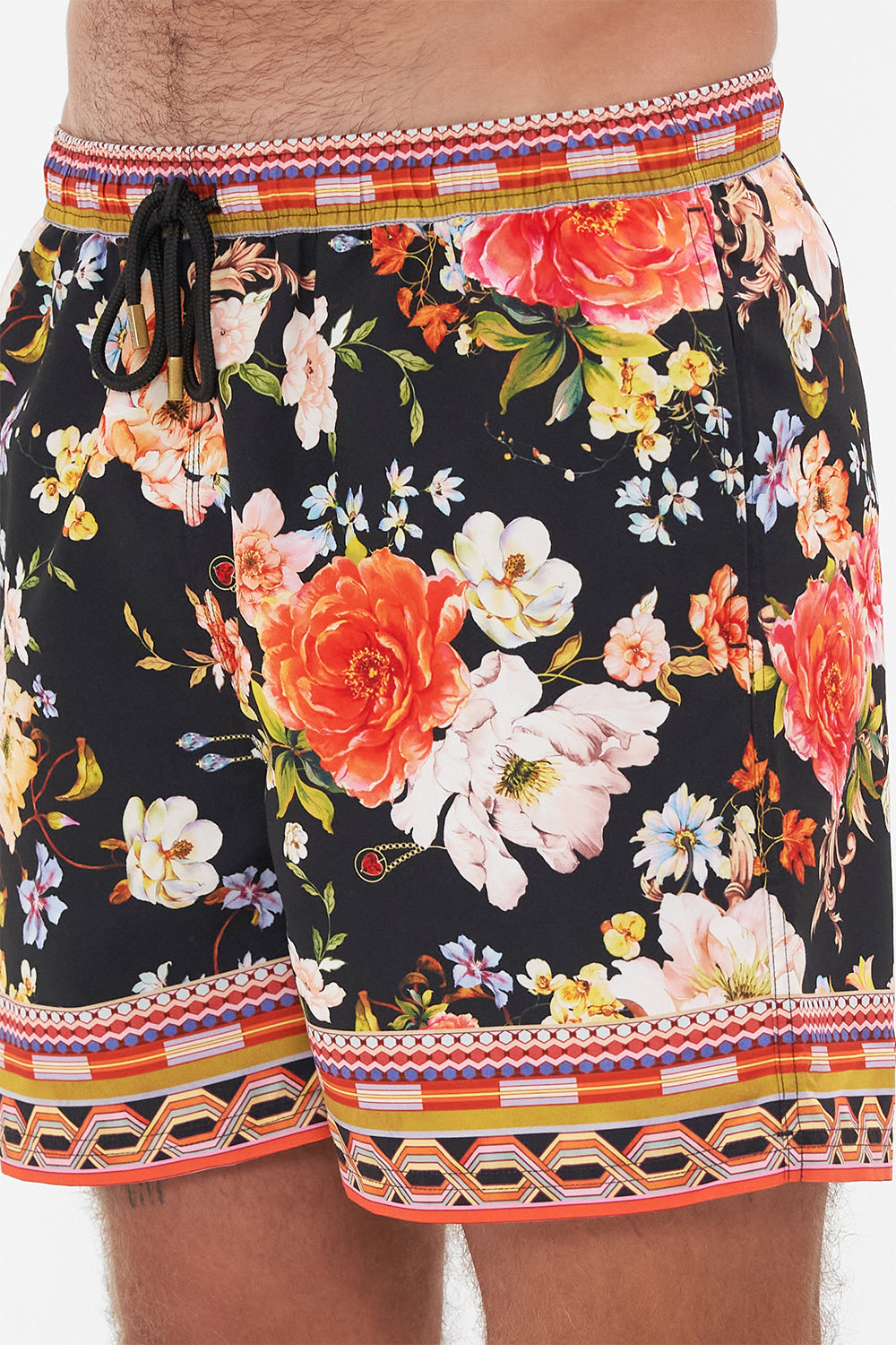 Detail view of model wearing Hotel Franks by CAMILLA mens black floral print boardshorts in Secret History print