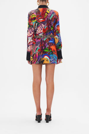 Back view of model wearing CAMILLA silk mini skirt in multicoloured Radical Rebirth print