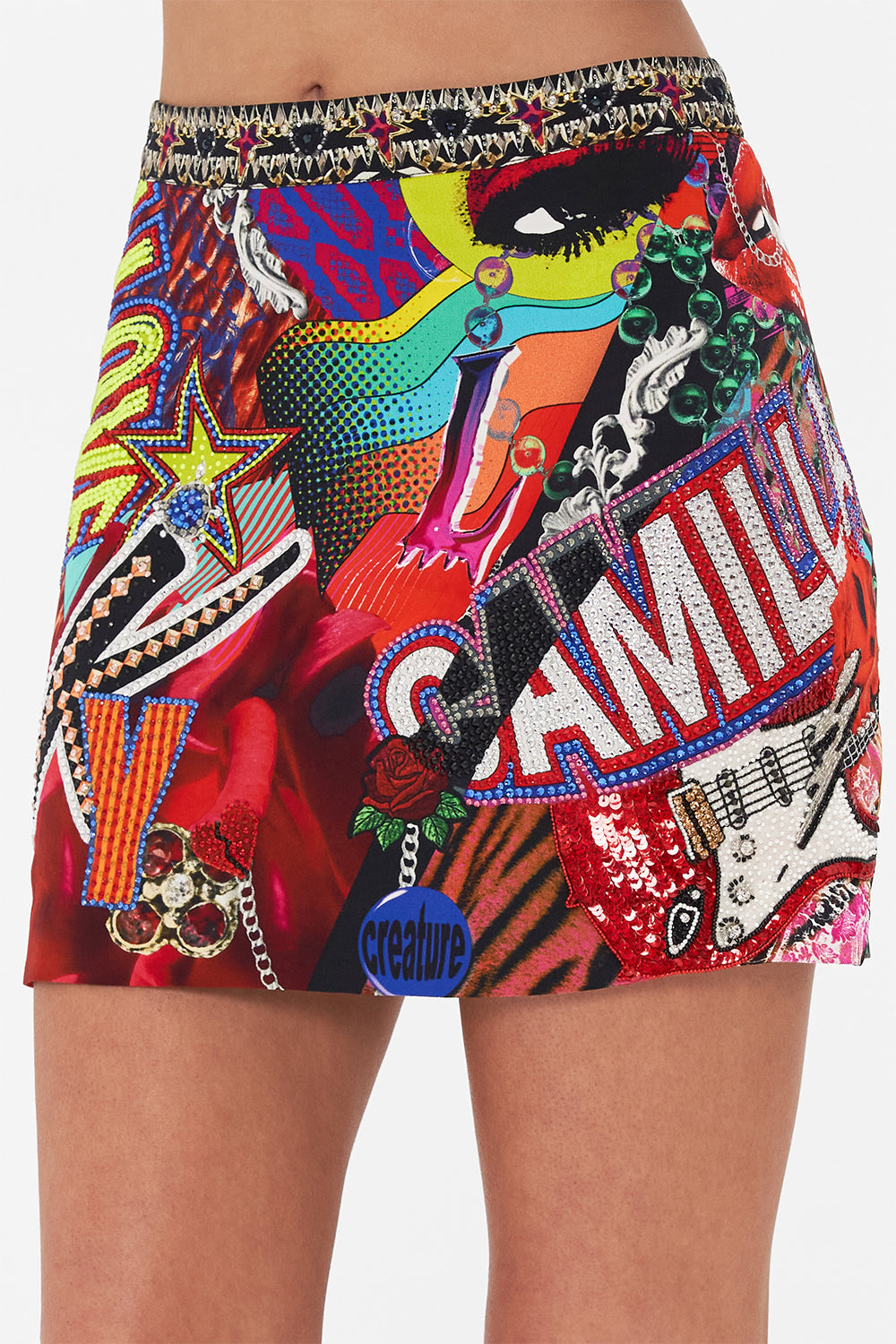 Detail view of model wearing CAMILLA silk mini skirt in multicoloured Radical Rebirth print