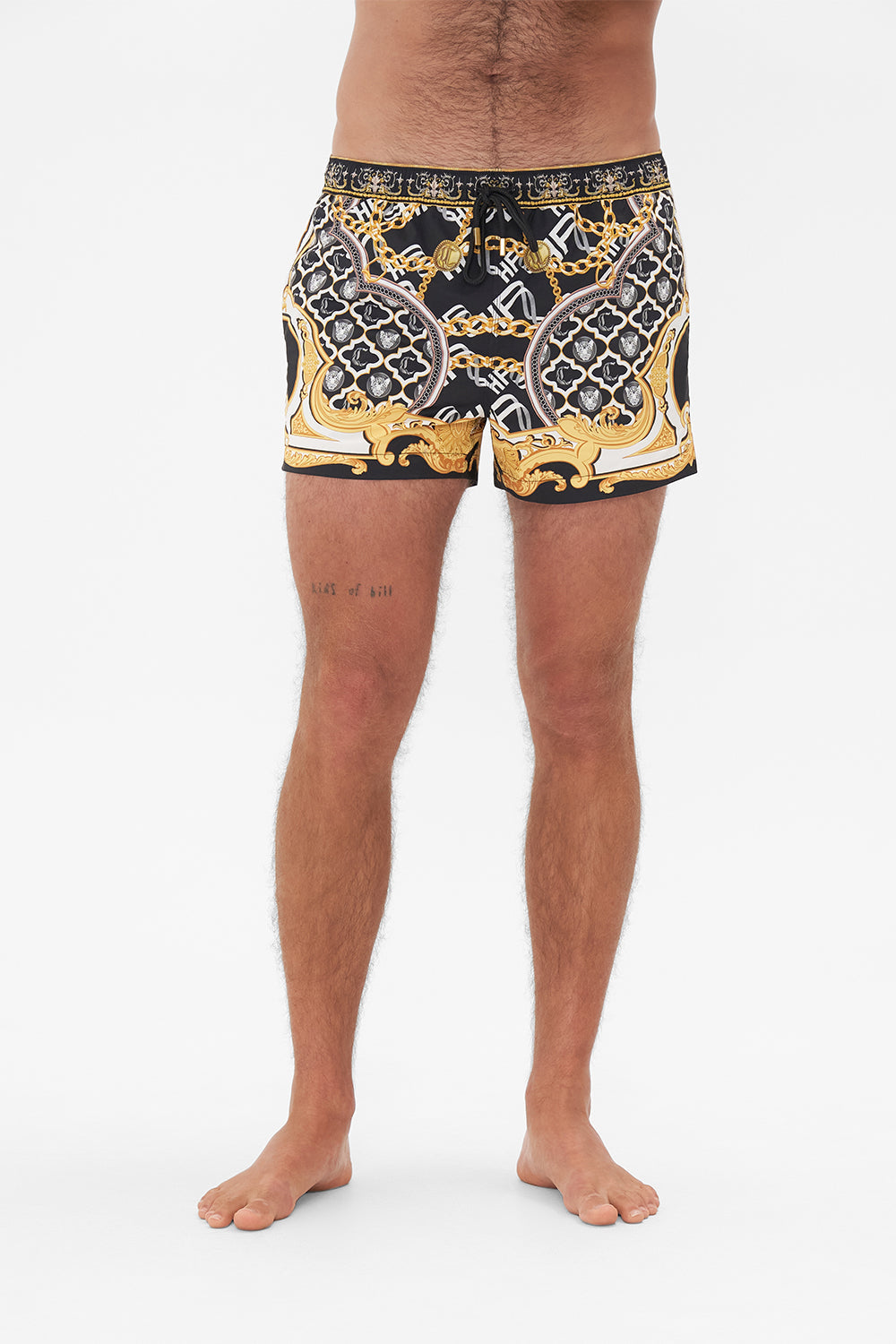 Crop view of model wearing Hotel Franks by CAMILLA mens black swim shorts in Tether Me Not print