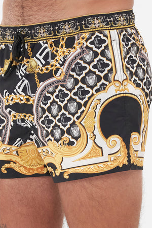 Detail view of model wearing Hotel Franks by CAMILLA mens black swim shorts in Tether Me Not print